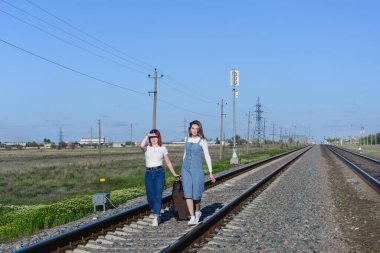 İki genç kadın büyük bir bavulu demiryolu ile taşıyorlar. Zorlu seyahat kavramı.