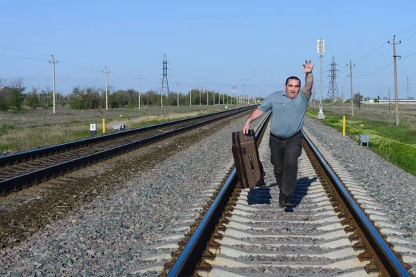 Bavullu bir adam tren yolu boyunca koşuyor. Trene geç kaldım..