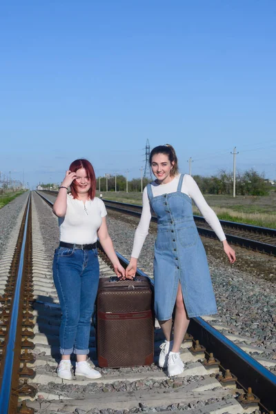 Δύο Νεαρές Γυναίκες Κουβαλάνε Μια Μεγάλη Βαλίτσα Στις Σιδηροδρομικές Γραμμές — Φωτογραφία Αρχείου