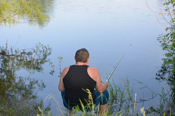 Männlicher Fischer Sitzt Mit Angelrute Ufer Des Flusses Und Fängt — Stockfoto