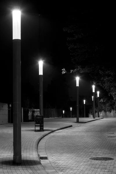Fila de luzes de rua em uma rua curva e calçada — Fotografia de Stock