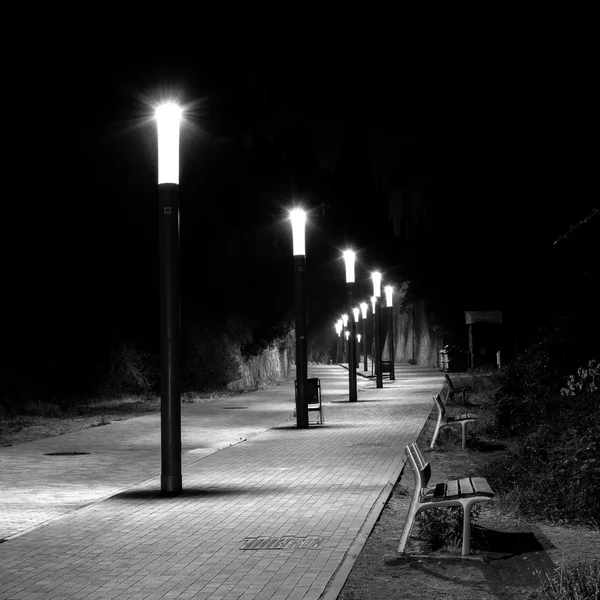 Fila de luzes de rua em uma rua curva e calçada — Fotografia de Stock