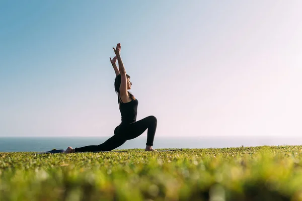 Siyahlı sıska kadın yoga antrenmanında vücudunu esnetiyor. Boşluğu kopyala