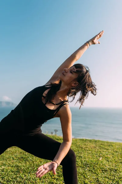 Açık havada siyah giyinmiş bir kadının portresi yoga yapıyor. Boşluğu kopyala
