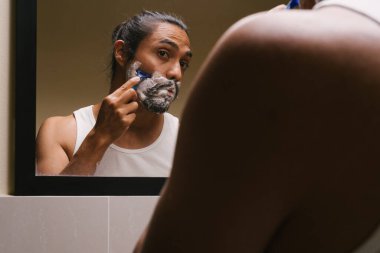 Latin adam banyoda tıraş oluyor.