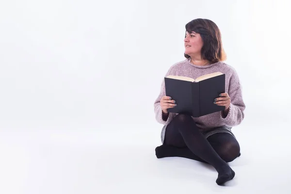 Kitaplı Bir Kadın Beyaz Arka Planda Otururken Sola Bakıyor Boşluğu — Stok fotoğraf