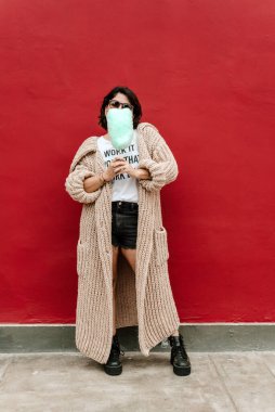 Vertical image of a woman with a water-green cotton candy on a red background. Urban image. Copy space