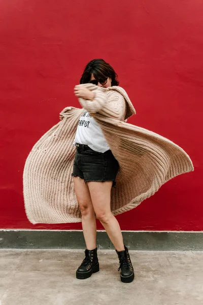 Image of a woman who plays with her sweater making it fly. Selective focus of woman spinning with her hand knitted sweater on a red background