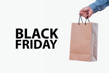 Üzerinde Kara Cuma yazan bir alışveriş çantası olan mavi uzun kollu bir adamın eli.