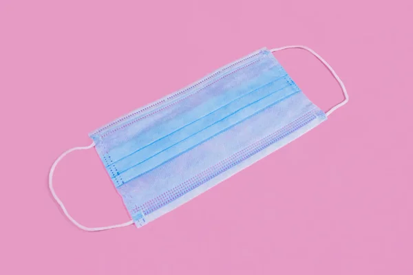 Medical mask on a pink background. mask that protects against viruses. Covers the mouth and nose to protect against viruses and bacteria on a pink background.