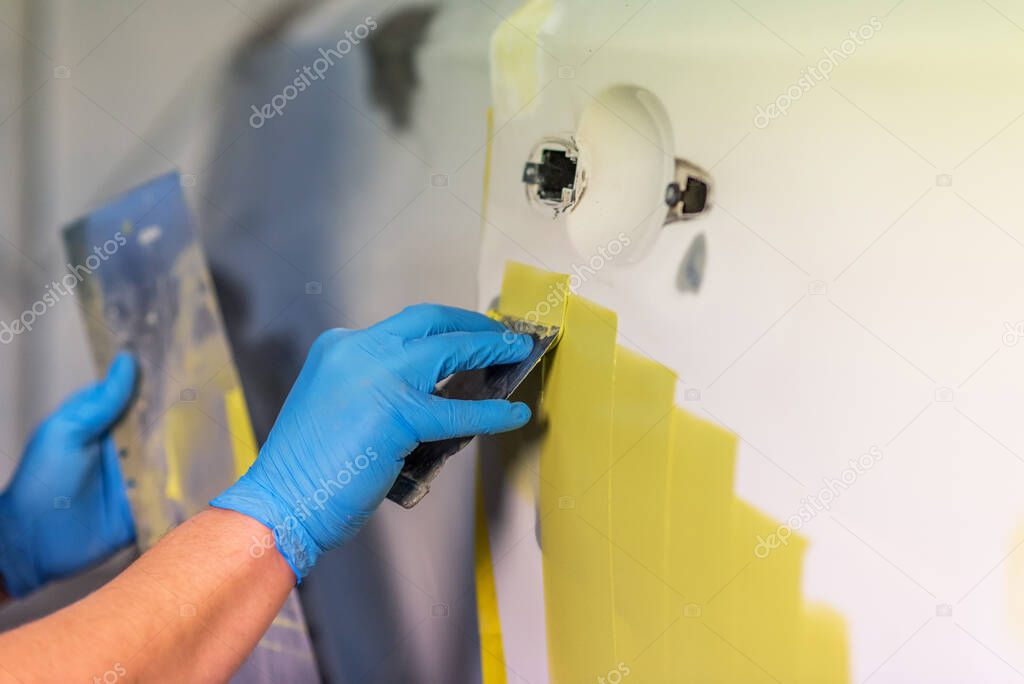 Preparation for painting a car element using emery sender by a service technician leveling out before applying a primer after damage to a part of the body in an accident in the vehicle workshop.
