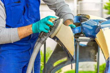 Araba tamirhanesinde araba cilalayan bir adamın elinde öğütücü..