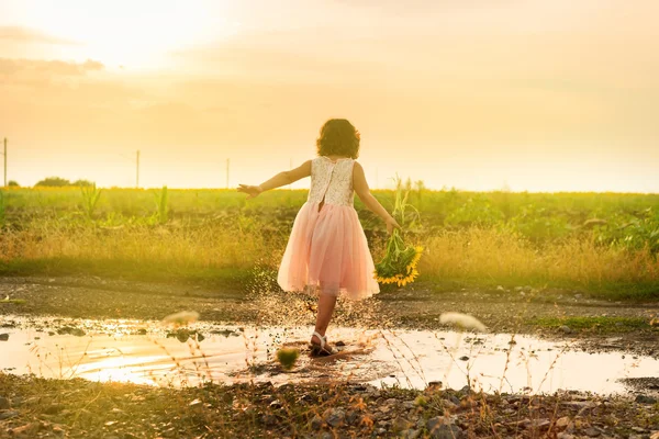 Süßes kleines Mädchen spielt in Pfütze Stockfoto