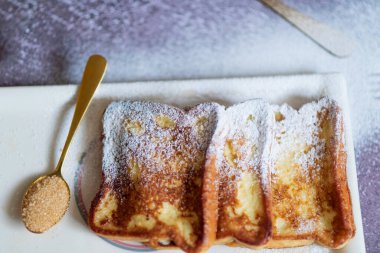 Gri arka planda tarçınlı geleneksel Fransız tostu. Geleneksel İspanyol usulü kızarmış ekmek