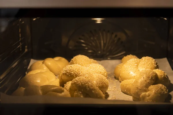 Piekę domowej roboty chleb chałki. Plecionka chała z nasionami sezamu na blasze w piekarniku — Zdjęcie stockowe