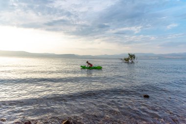 Genç bir çocuk mavi suyla deniz şeklinde şişme bir timsahın üzerinde yüzüyor. Güneşli bir günde güzel bir tatil..