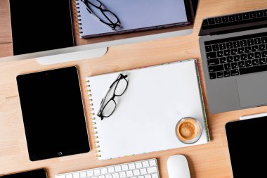 Ofis malzemeleri yerleştirilmiş ahşap bir masanın üst görüntüsü. İbranice Klavye