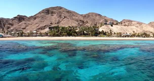 Blick auf den Strand vom Wasser aus, vor dem Hintergrund der Wüstenberge und der Palm Avenue. Türkisklares Wasser mit Korallenriffen — Stockvideo