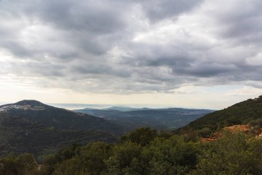 Gün doğumunda, mavi gökyüzü ve bulutların dramatik sırtına karşı, bir dağ sırası ve yeşil bir vadi manzarası. Yüksek kalite fotoğraf. Seyahat konsepti yürüyüşü. Kuzey İsrail Bölgesi