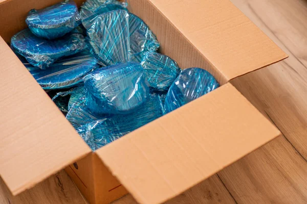 Artículos de vidrio envueltos con nylon azul en la parte inferior de una caja de cartón. Artículos de vidrio envueltos en una caja —  Fotos de Stock