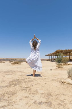 Bir kadın çölde durur ve ufka bakar. Rüzgarda çırpınan beyaz elbiseler. Rahatlama, iç görünüm, meditasyon, iç huzur kavramı