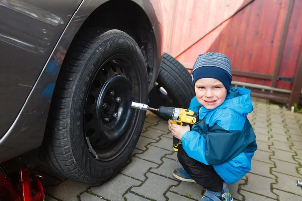 Menino montado pneus em um carro . — Fotografia de Stock