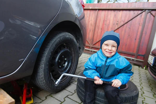 Menino montado pneus em um carro . — Fotografia de Stock