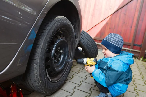 Pojke monterade däck på en bil. — Stockfoto