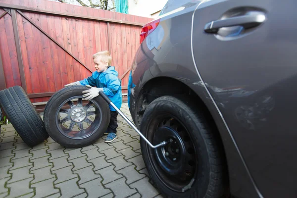 Boy mounted tires on a car. — Stock Photo, Image