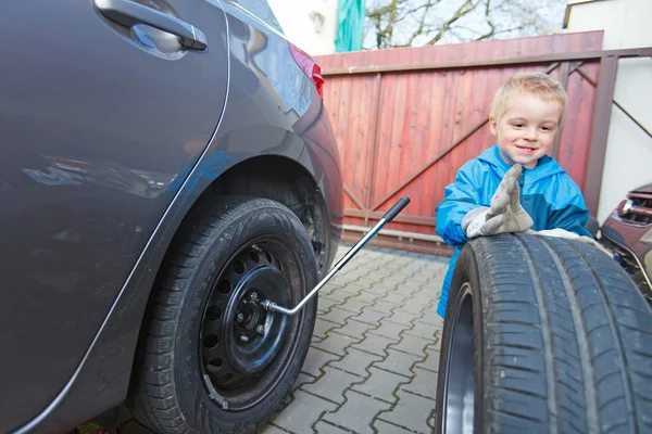 Мальчик устанавливал шины на машину . — стоковое фото