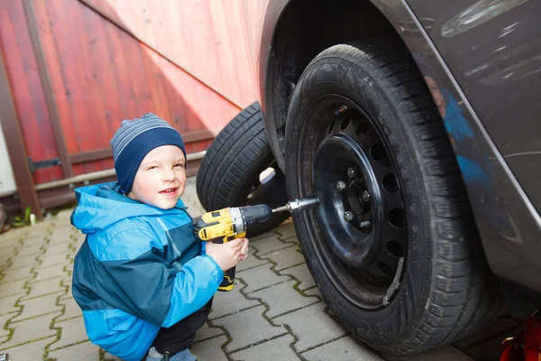 Menino montado pneus em um carro . — Fotografia de Stock