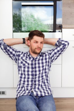 Çekici bir genç adam dinlenme içinde modern bir mutfak. 