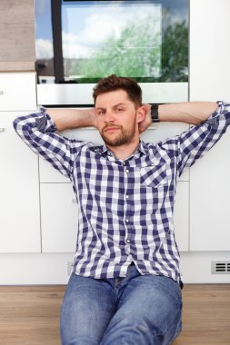 Çekici bir genç adam dinlenme içinde modern bir mutfak. 