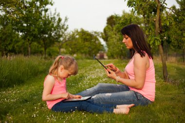 Anne ve kızı bir tablet üzerinde çalışan.