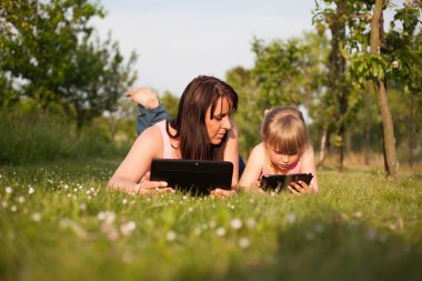 Anne ve kızı bir tablet üzerinde çalışan.