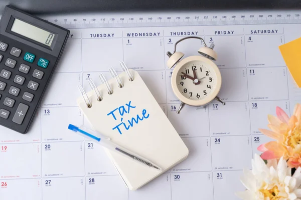 Takvimde Vergi Saati ile yazılmış hesap makinesinin ve defterin üst görünümü veya kopyalama alanı ile planlama.