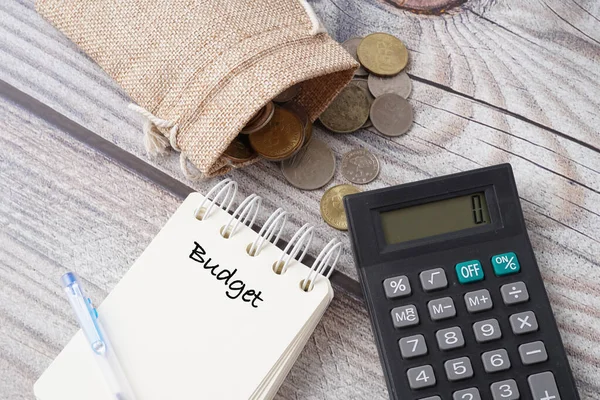Ahşap zemin üzerinde madeni paralar ve hesap makinesi olan bütçe kavramının en üst görünümü