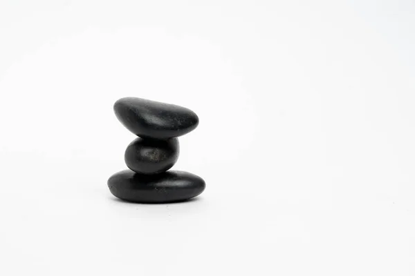 Beyaz arka planda izole edilmiş siyah taş yığını, kulede çakıl taşı grubu, uyum ve denge.
