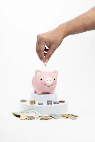 Beyaz arka planda izole edilmiş pembe kumbaraya para koymak. Tasarruf veya yatırım kavramı