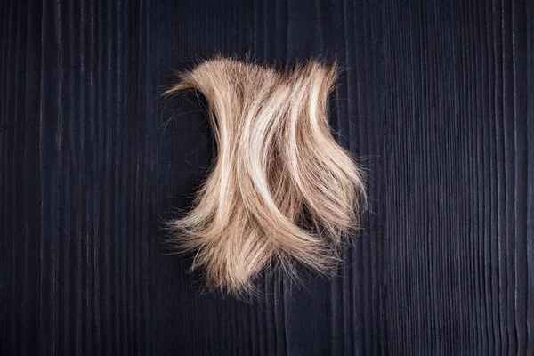 Blond Golvend Haarlok Zwart Houten Achtergrond Close Afgesneden Natuurlijk Blond — Stockfoto