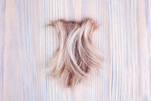 Blond Faliste Włosy Zamek Jasnym Drewnianym Tle Zbliżenie Odciąć Naturalne — Zdjęcie stockowe