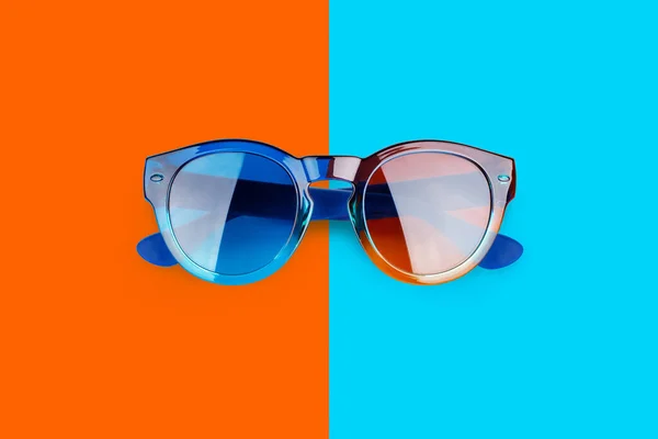 Sunglasses vibrant blue and orange red background close up top view, fashion sunshades on colorful backdrop, trendy modern eyeglasses, summer beach holidays concept, ultraviolet protection, copy space