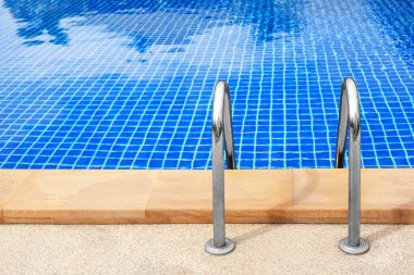 Yüzme havuzu girişi merdiveni, metal tutucu bar merdiveni, yüzme havuzu ahşap güverte kenarı, havuz kenarı mavi su arka planı, deniz kıyısı yaz tatili, tatil eğlencesi konsepti, fitness sporu.