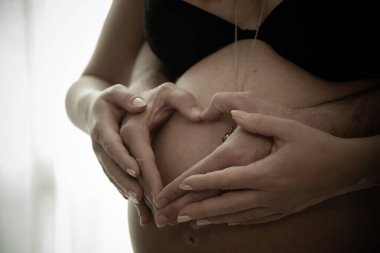 İtalya, Nisan 2021. Güzel hamile kadın ve yakışıklı kocasının göbeğine sarılırken görüntüsü.