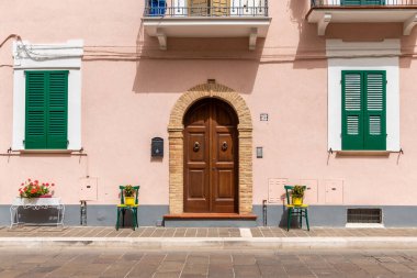 Haziran 2021, San Vito Chietino, İtalya. San Vito Chietino 'nun ana meydanı. Evlerin girişinin yanındaki eski renkli sandalyeler. Yorgun gezginler ve saksılar için..