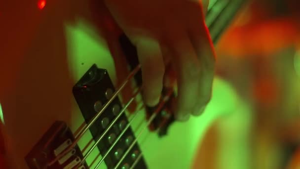 Basçı erkek eli elektro bas gitar çalıyor ve tellere dokunuyor. Bir rock konserinde, müzisyen müzik dinlerken telleri çalar. — Stok video