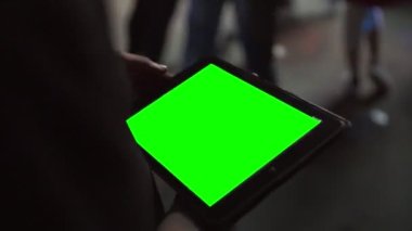 Konserde Mans 'ın elleri siyah tablet bilgisayarı ve boş yeşil masaüstü ekranı tutuyor. Bir aydınlatma tasarımcısı dijital tablet bilgisayar ekranının yeşil bir kopyasını tutuyor. Arka planda bir...