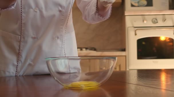 Tatlı bir hamur işi şefinin yumurtayı bir kaseye kırdığı ve mutfak süpürgesiyle karıştırdığı görüntüler. Yavaş çekim — Stok video