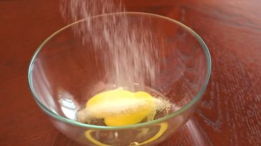 Mutfakta kek fırıncısı pişirmek. Yumurta sarısı ve şekerin döküldüğü yakın plan kaseler. Ev yapımı kekler için yavaş çekimde pişirme. Bir kasede taze yumurta ana malzemedir.