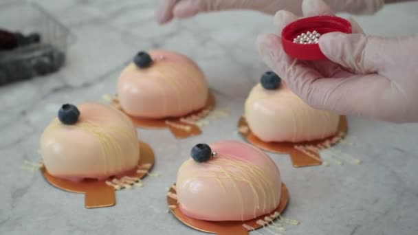 Zbliżenie, szef kuchni ręcznie zdobi srebrnymi koralikami ciasto z jagodami w postaci serca na stole w kuchni, gotowanie pyszny słodki deser — Wideo stockowe